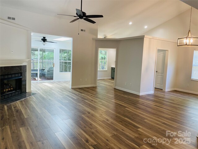 unfurnished living room featuring visible vents, a fireplace, high vaulted ceiling, dark wood finished floors, and ceiling fan with notable chandelier