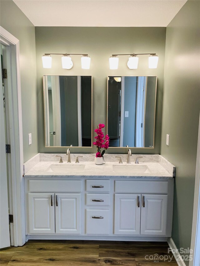 bathroom featuring double vanity, a sink, and wood finished floors
