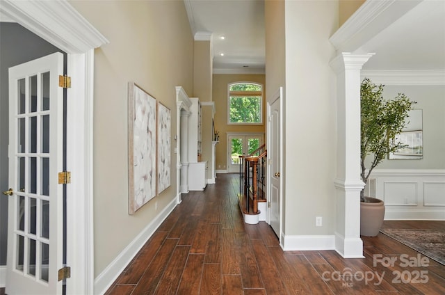 hallway featuring ornate columns, dark wood finished floors, and ornamental molding