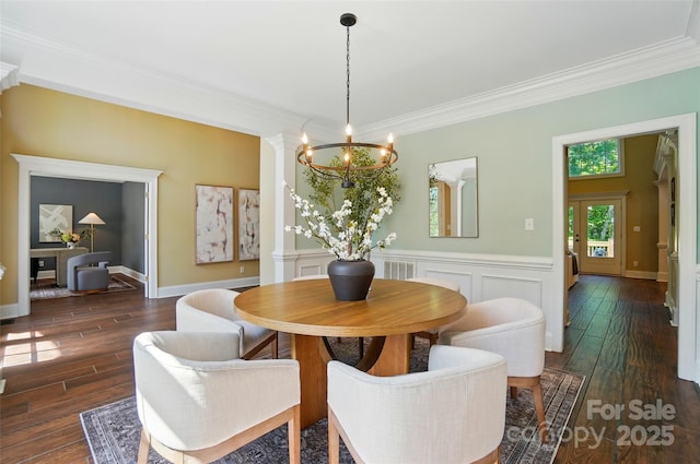 dining space featuring an inviting chandelier, ornamental molding, and wood finished floors