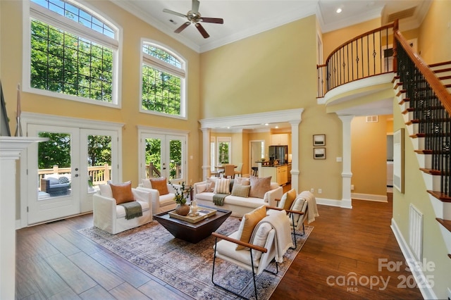 living area featuring decorative columns, a towering ceiling, dark wood-style floors, and stairway