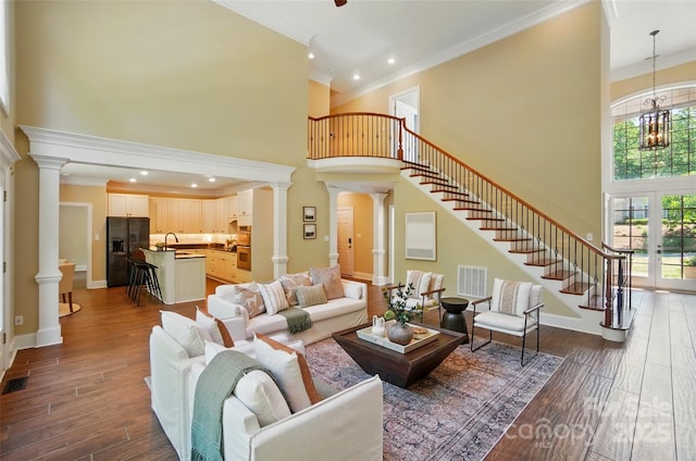 living room with decorative columns, a high ceiling, visible vents, and stairway