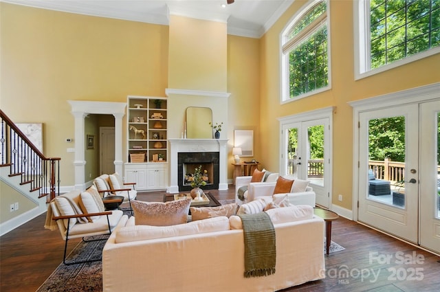 living room featuring crown molding, a wealth of natural light, french doors, and a towering ceiling