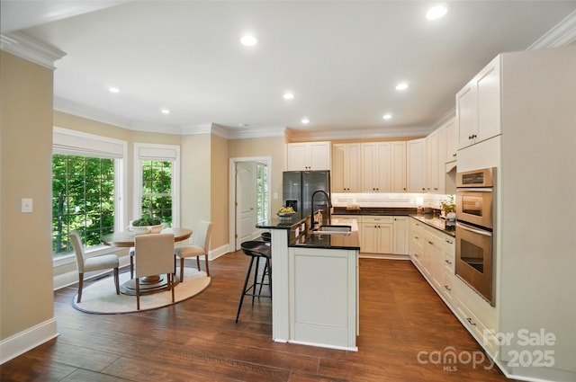kitchen featuring crown molding, dark countertops, stainless steel double oven, a sink, and refrigerator with ice dispenser