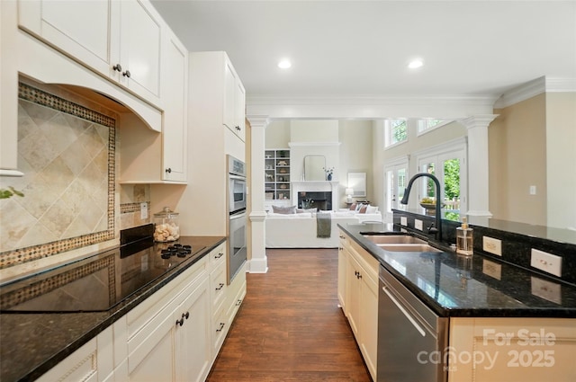 kitchen featuring dark wood-type flooring, a sink, decorative columns, and stainless steel appliances