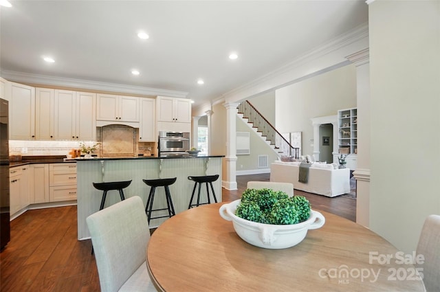 dining room featuring recessed lighting, ornamental molding, ornate columns, and dark wood-type flooring