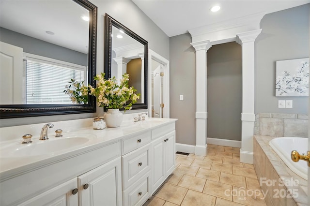 bathroom with a garden tub, tile patterned flooring, decorative columns, baseboards, and a sink