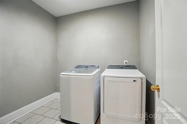 laundry area with light tile patterned flooring, laundry area, washing machine and dryer, and baseboards