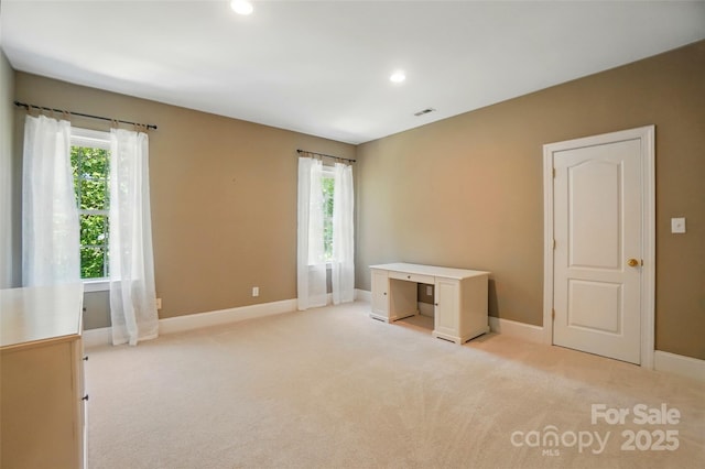 unfurnished bedroom featuring light colored carpet, baseboards, and multiple windows