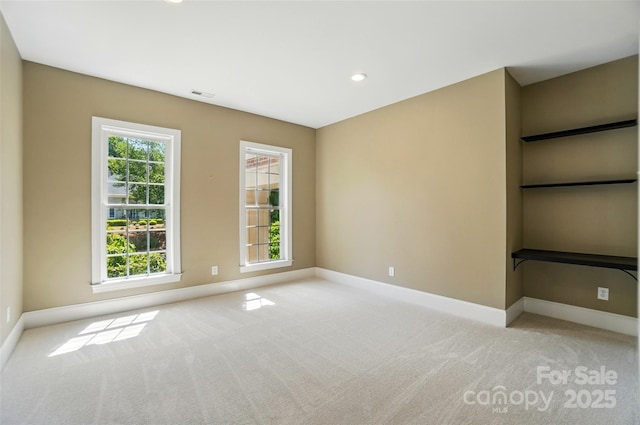 unfurnished room with a healthy amount of sunlight, baseboards, and light carpet