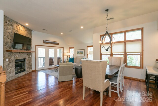 220 Stoney Falls Loop Unit C/2, Burnsville, NC 28714 - dining space with dark wood-style flooring, a stone fireplace, visible vents, vaulted ceiling, and a chandelier