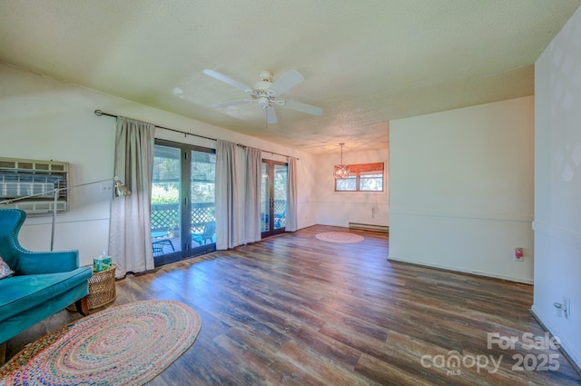 unfurnished living room with a textured ceiling, a baseboard heating unit, wood finished floors, and ceiling fan with notable chandelier