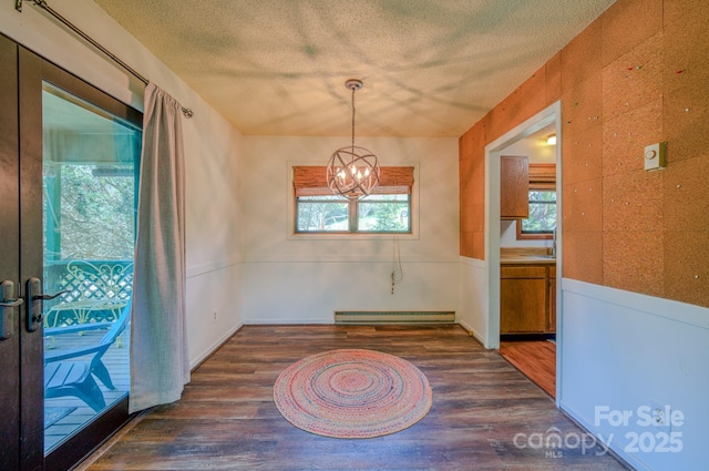 unfurnished dining area featuring wood finished floors, baseboard heating, and a healthy amount of sunlight