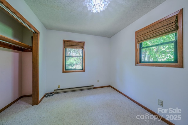 unfurnished bedroom with carpet floors, a closet, baseboards, baseboard heating, and a textured ceiling