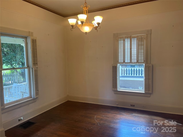 unfurnished room with dark wood-style flooring, a chandelier, baseboards, and ornamental molding
