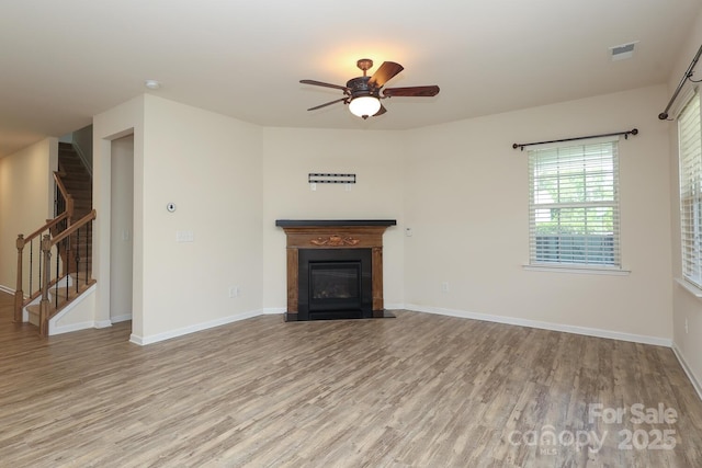 309 Kentmere Ln, Clover, SC 29710 - unfurnished living room featuring ceiling fan, visible vents, a fireplace with flush hearth, wood finished floors, and stairway