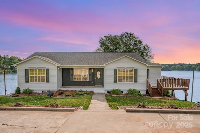 view of front facade featuring a water view, crawl space, a shingled roof, and a front lawn