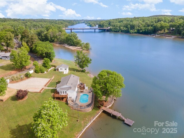 birds eye view of property with a water view and a wooded view