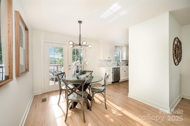 dining room featuring baseboards, light wood finished floors, a chandelier, and a wealth of natural light