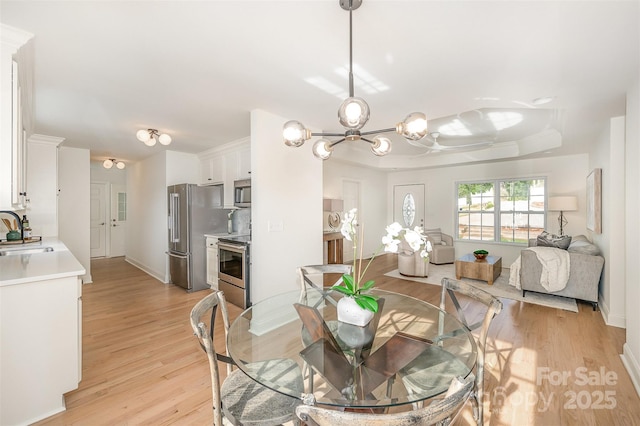dining space featuring light wood-type flooring, baseboards, and a notable chandelier
