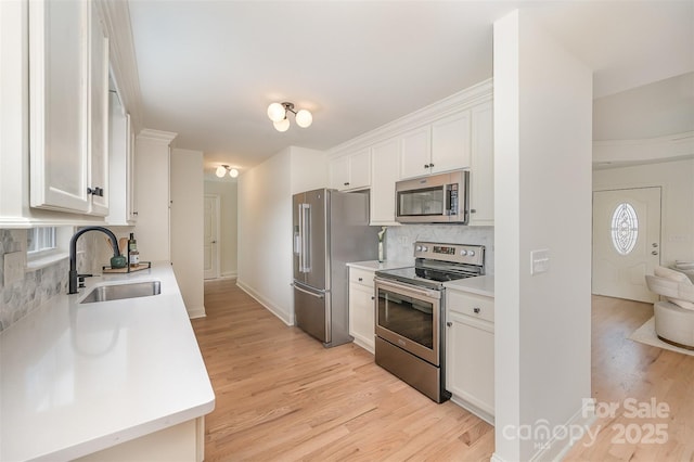 kitchen with a sink, decorative backsplash, light wood-style floors, and stainless steel appliances