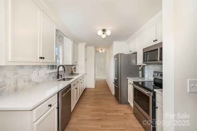 kitchen with decorative backsplash, light wood-style floors, white cabinets, a sink, and stainless steel appliances