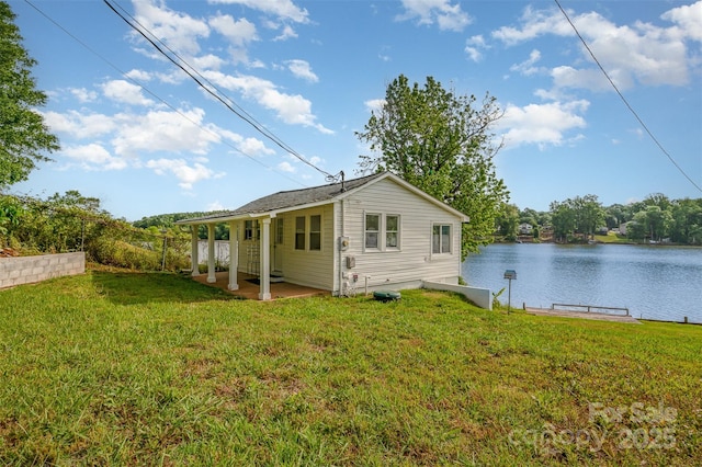 back of property with a yard, a water view, and a patio