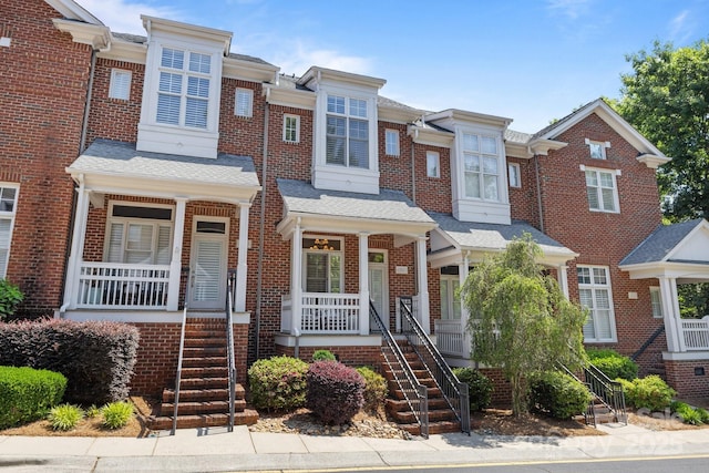 multi unit property featuring a porch, stairway, and brick siding