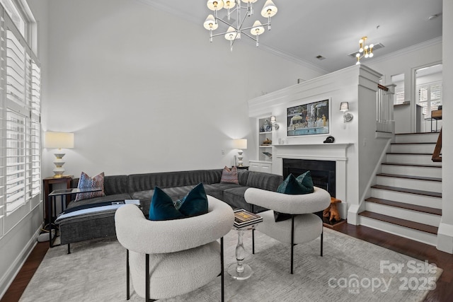 living area featuring a notable chandelier, baseboards, stairs, wood finished floors, and a fireplace