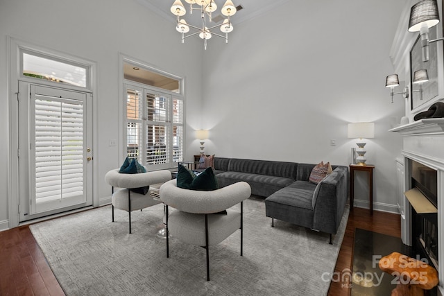 living room featuring baseboards, an inviting chandelier, crown molding, and wood finished floors