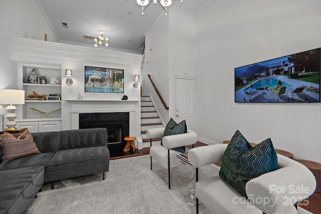 living room with ornamental molding, visible vents, built in features, stairs, and a fireplace with flush hearth