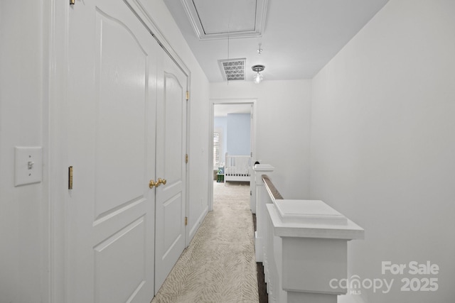 hall with light colored carpet, attic access, and visible vents