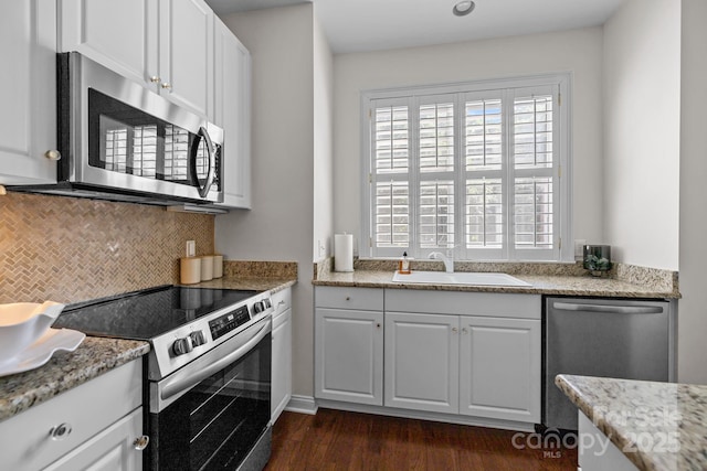 kitchen featuring a sink, backsplash, white cabinetry, dark wood-style floors, and appliances with stainless steel finishes