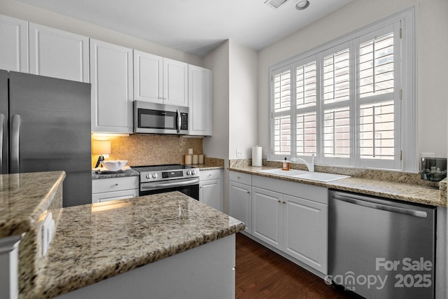 kitchen featuring dark wood finished floors, a sink, white cabinetry, decorative backsplash, and appliances with stainless steel finishes