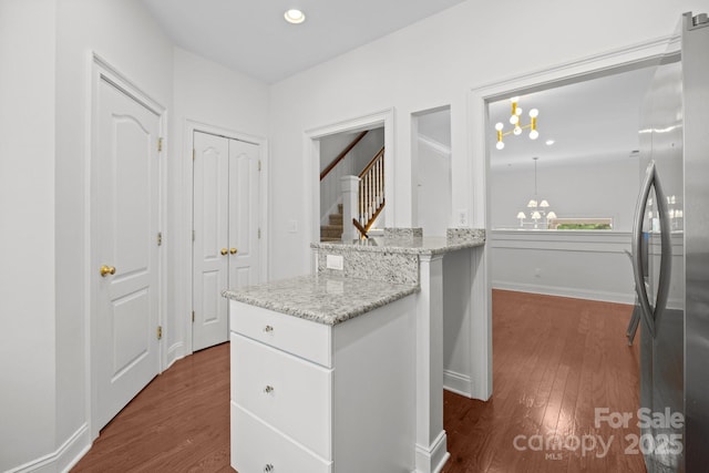 interior space featuring freestanding refrigerator, white cabinetry, dark wood-type flooring, and light stone countertops