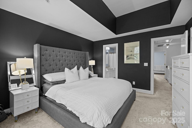 bedroom with baseboards, ensuite bath, attic access, and light colored carpet