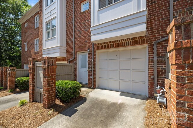 exterior space featuring driveway, brick siding, an attached garage, and fence