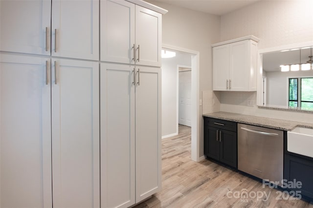 kitchen with stainless steel dishwasher, white cabinetry, light stone countertops, and light wood finished floors