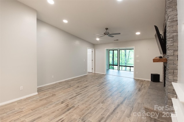 unfurnished living room featuring a stone fireplace, a ceiling fan, recessed lighting, and light wood-style flooring