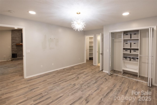 unfurnished bedroom featuring light wood-type flooring, baseboards, and an inviting chandelier