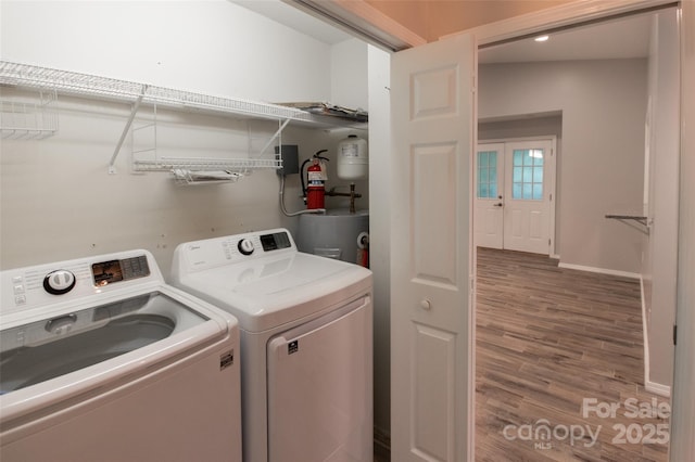 clothes washing area with laundry area, wood finished floors, baseboards, water heater, and washer and clothes dryer