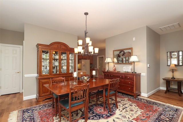 2114 N Castle Ct, Matthews, NC 28105 - dining area featuring baseboards, light wood finished floors, an inviting chandelier, and visible vents