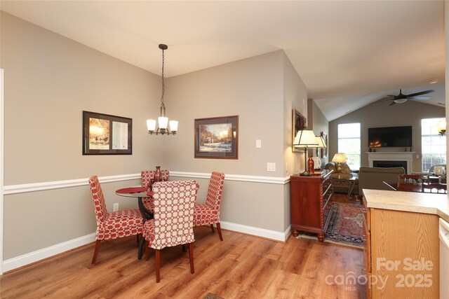 2114 N Castle Ct, Matthews, NC 28105 - dining area featuring light wood-style floors, baseboards, a fireplace, and lofted ceiling