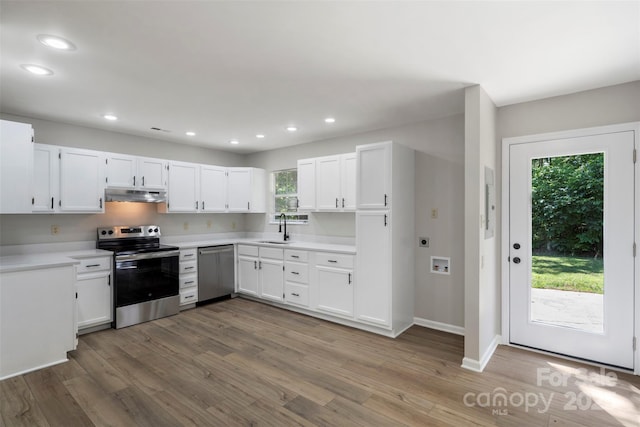 7525 Cedarbrook Dr, Charlotte, NC 28215 - kitchen featuring appliances with stainless steel finishes, wood finished floors, a sink, under cabinet range hood, and white cabinetry