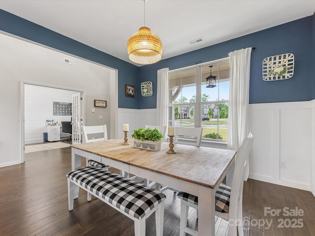 dining space with visible vents, wainscoting, and a decorative wall