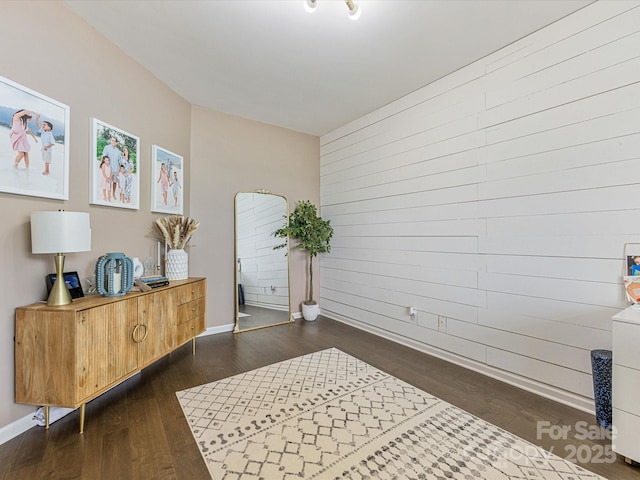 office area with baseboards, wood walls, and dark wood-style flooring