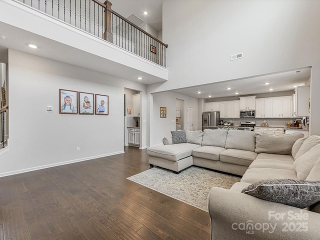 living room featuring a high ceiling, recessed lighting, baseboards, visible vents, and dark wood-style floors