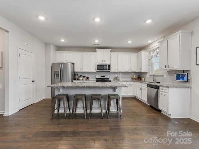 kitchen featuring decorative backsplash, a kitchen breakfast bar, stainless steel appliances, and white cabinetry