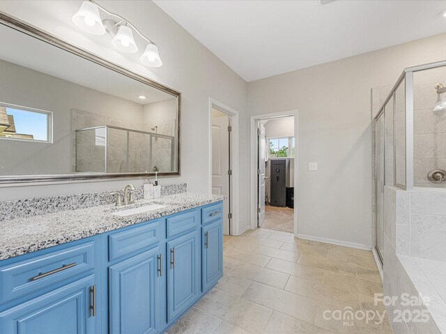 bathroom with a healthy amount of sunlight, vanity, baseboards, and a stall shower