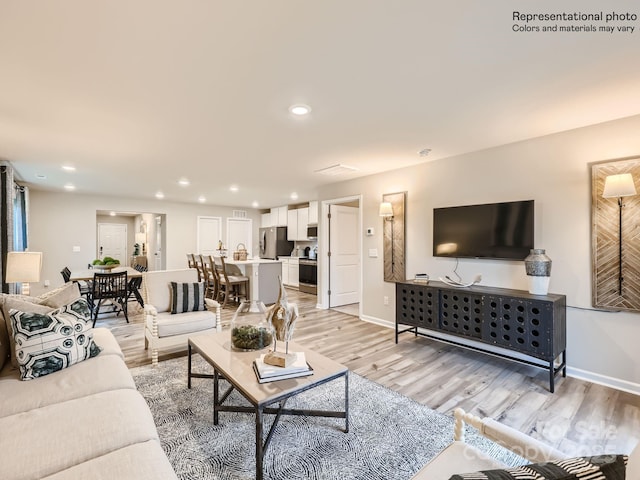 living room featuring recessed lighting, baseboards, and light wood finished floors